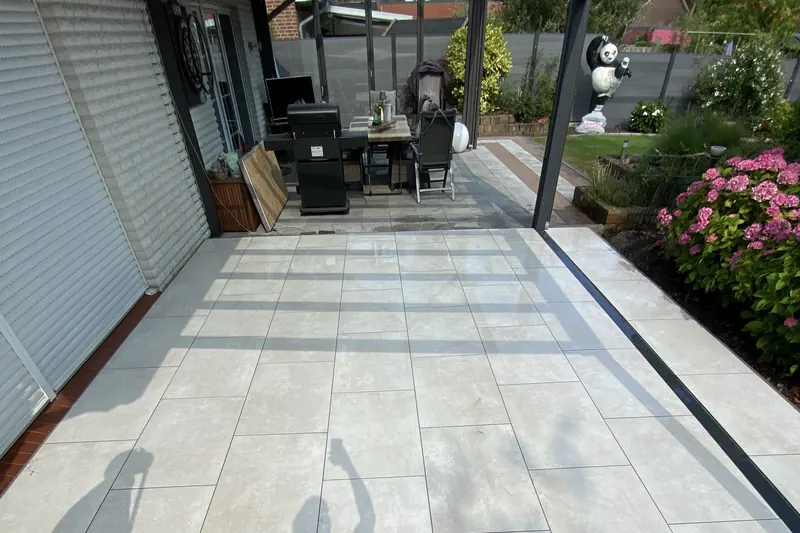 Großformatige Keramikterrasse mit Überdachung und angrenzendem Beet